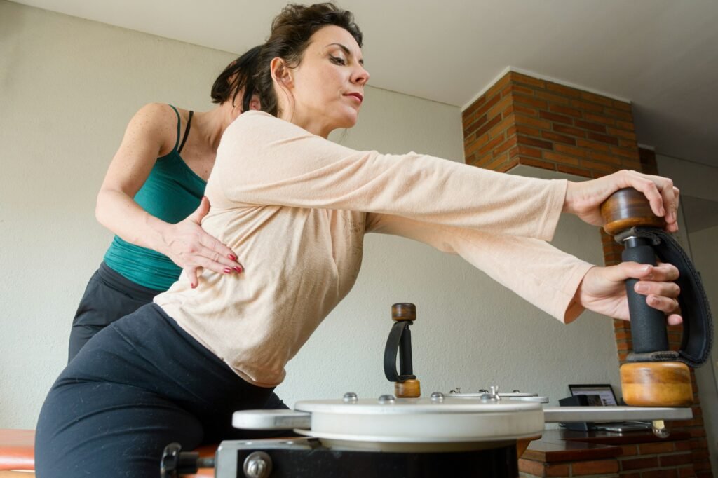 rehabilitation instructor correcting her student's back posture during training on exercise machine